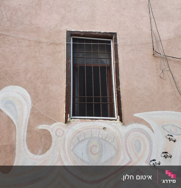 חלון עם מסגרת מתכתית על קיר צבוע